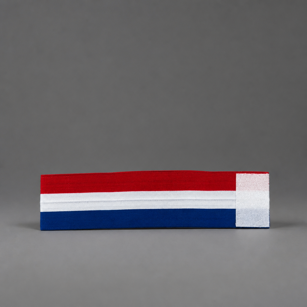 A rectangular fabric patch featuring horizontal red, white, and blue stripes with a white vertical stripe on the right side, photographed on a neutral gray background. Croatia Captain Armband