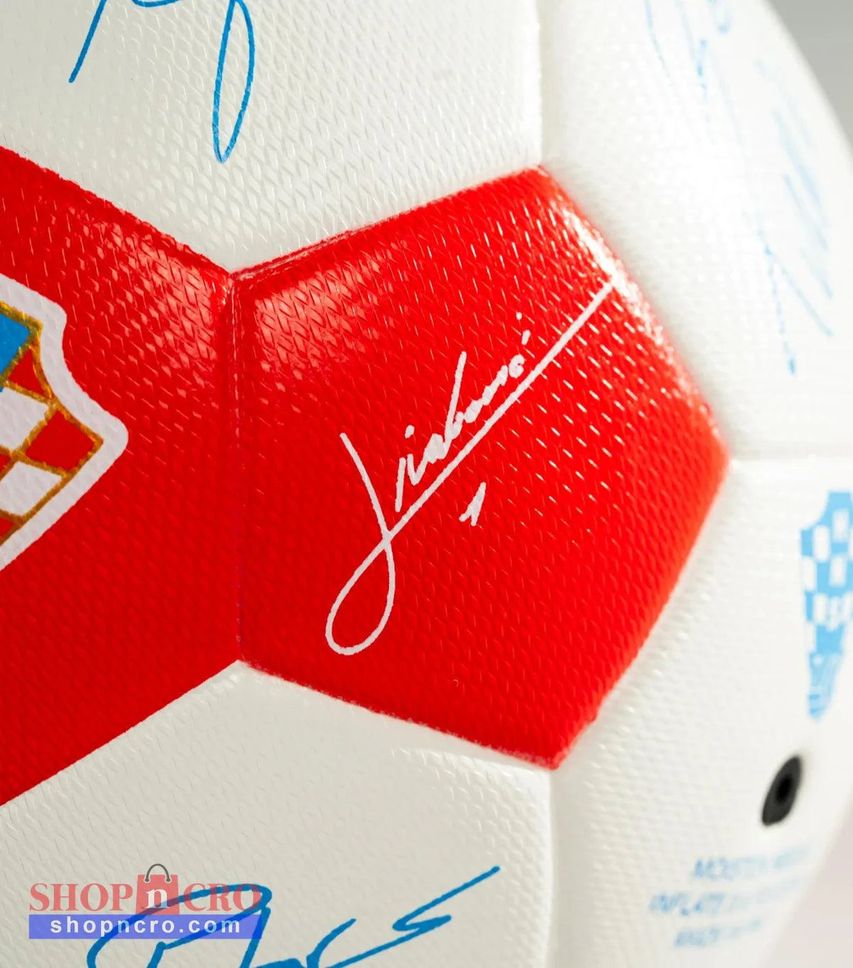 Close-up of a soccer ball with red and blue signatures on a white background