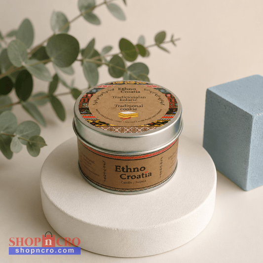 Scented Candle – Traditional Cookie (Ethno Croatia) Tin of 'Ethno Croatia' cookies on a white pedestal with a plant and blue block in the background. snc shopncro