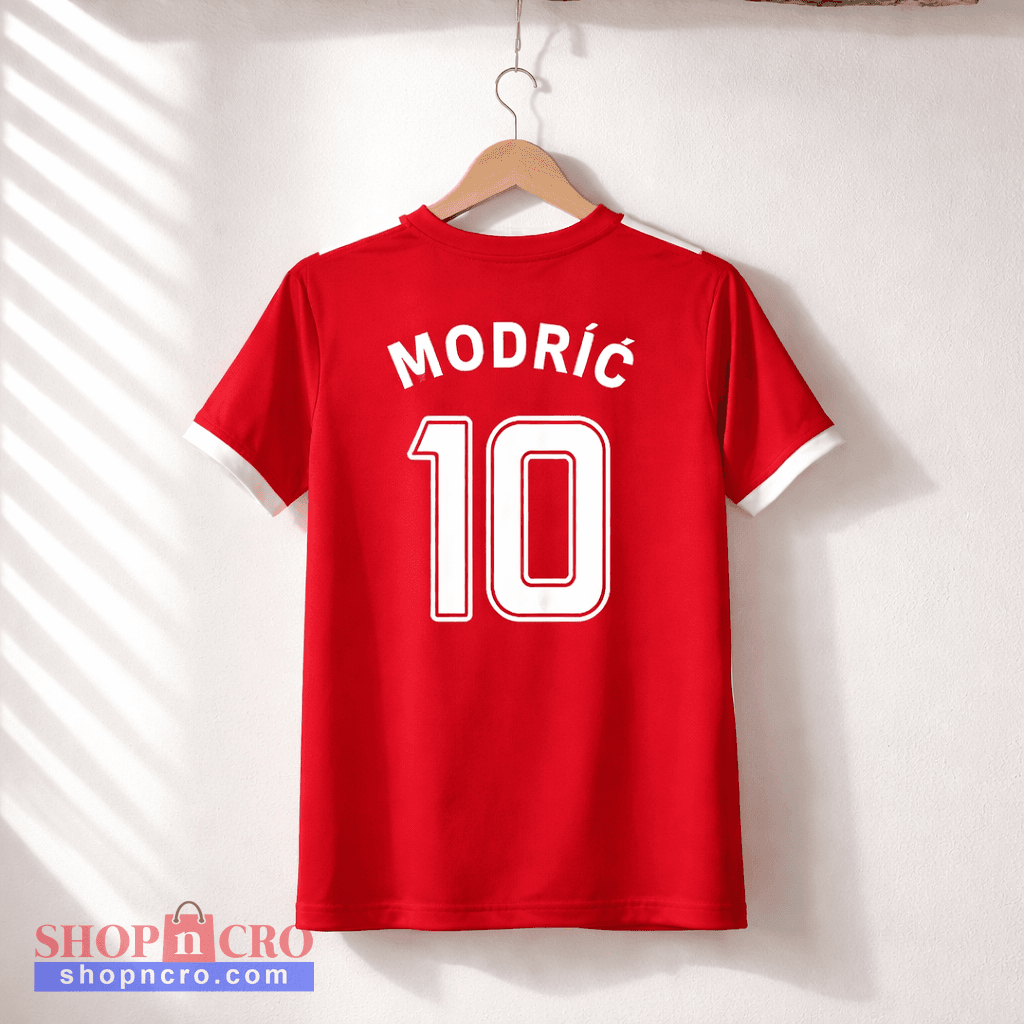 Red sports jersey with 'Modric 10' on a hanger against a white wall.