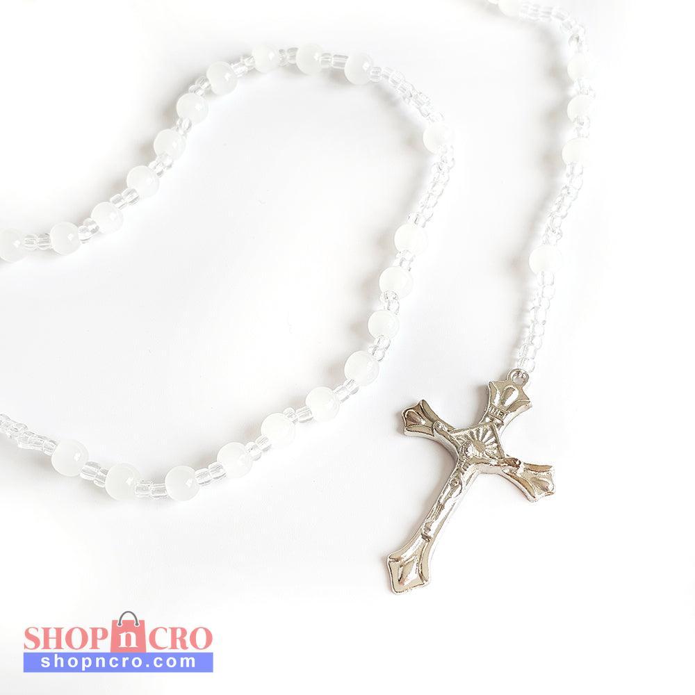 White Bead Catholic Rosary – Silver Crucifix Silver cross pendant on a white beaded necklace against a white background