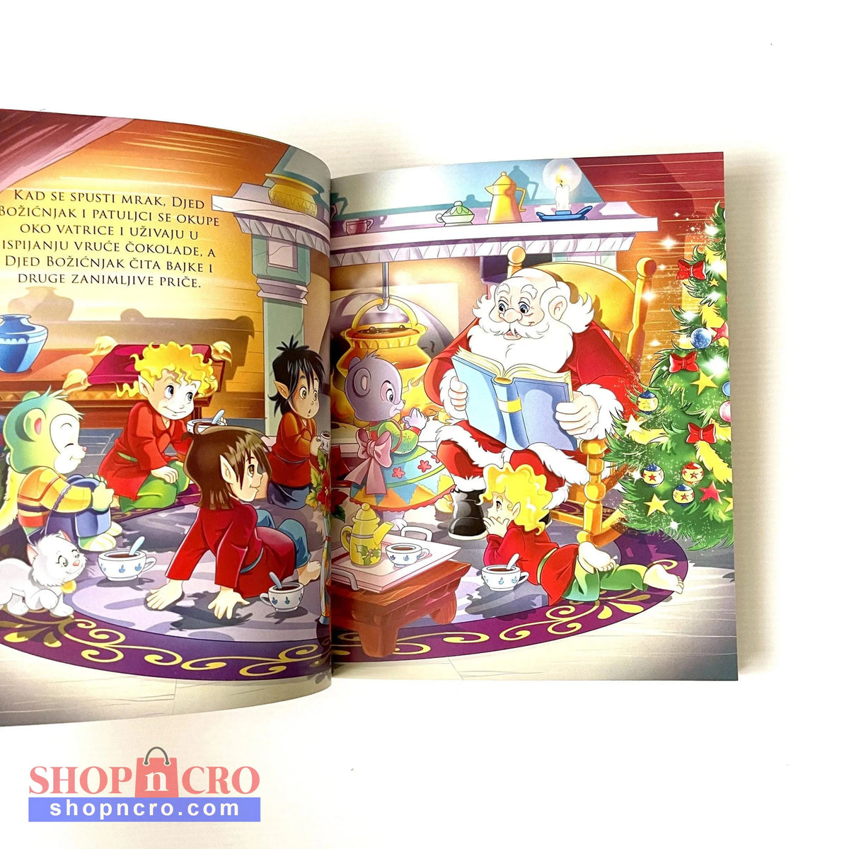 Čarobne priče - Božićne priče Open book with colorful illustrations of Santa Claus and children around a Christmas tree.