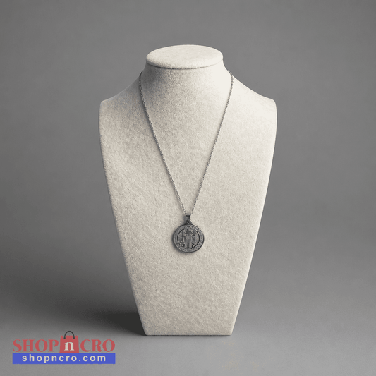 Croatian Medallion Necklace – St. Benedict Catholic Pendant A silver pendant necklace displayed on a textured off-white jewelry bust against a neutral gray background. The pendant is circular with an engraved design.