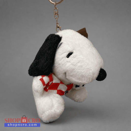 A plush Snoopy keychain charm featuring the character in a white and black color scheme, wearing a red and white checkered scarf, suspended from a gold metal key ring against a neutral gray background. Singing Croatian Fan Puppy – Hanging Plush Toy