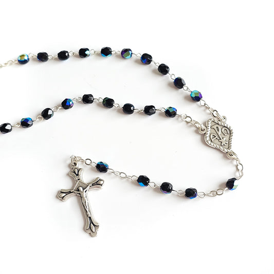 Black Crystal Catholic Rosary with Silver Crucifix and Alpha Omega Centerpiece Rosary with blue beads and silver crucifix on a white background