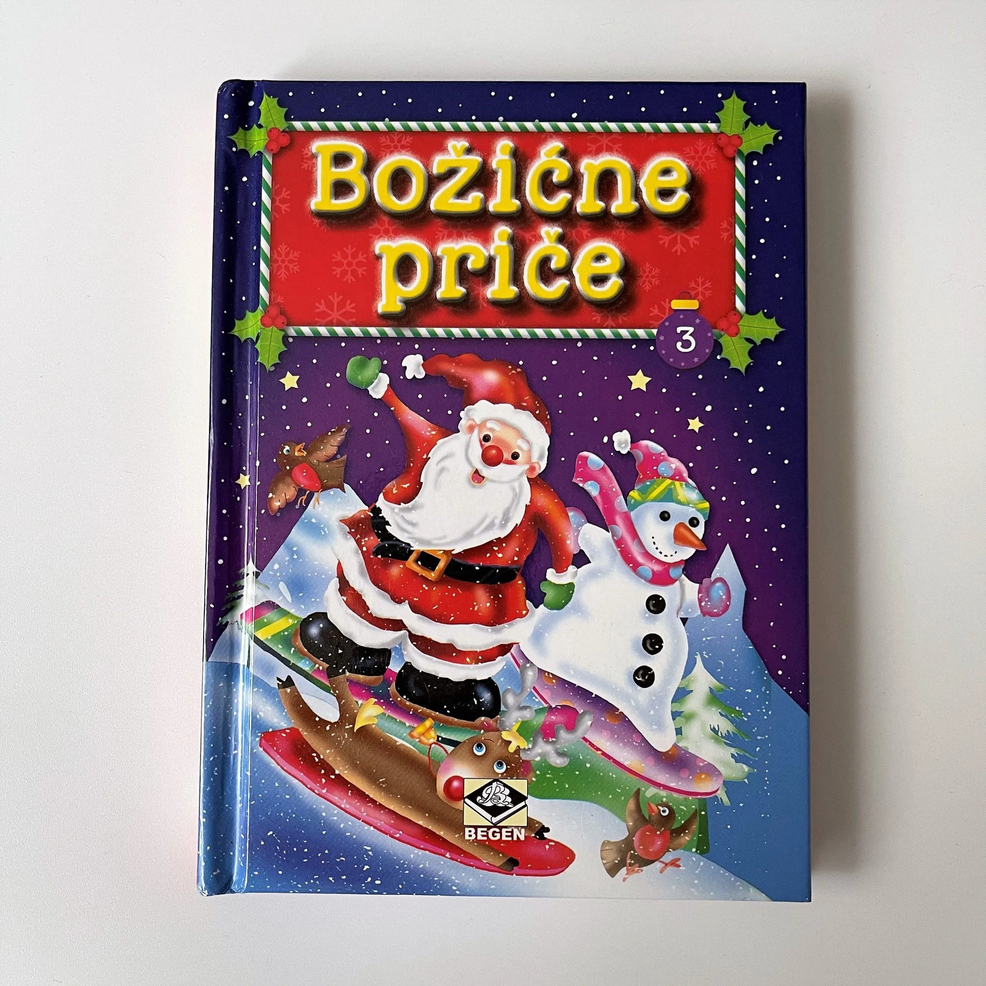Božićne Priče Book cover with Santa Claus and snowman on a snowy background, featuring the text 'Boōzièe príce'.