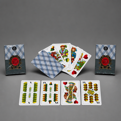 A game of cards deck set displayed on a neutral gray background, featuring the blue-and-white plaid deck box, two additional deck boxes, a fan of illustrated cards, and four face-up cards showing green and gold suit designs. Croatia BELOT Playing Cards