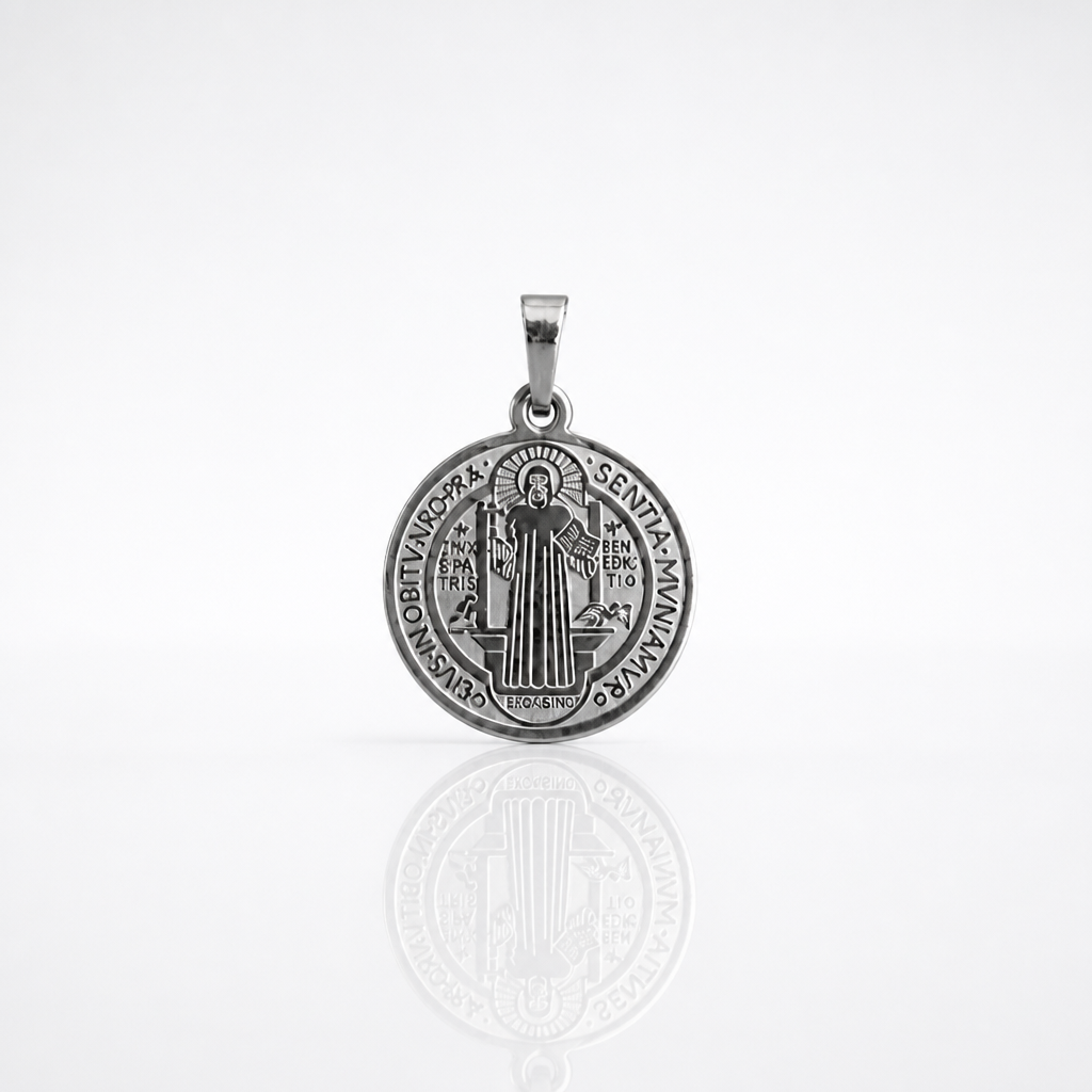 Croatian Medallion Necklace – St. Benedict Catholic Pendant A round silver Saint Benedict medal pendant with an engraved depiction of Saint Benedict and the inscription 'DE OMNIPOTENTE DEI TRINA MAXIMA SENTIA SANCTUS BENEDICTUS', shown on a reflective white surface.