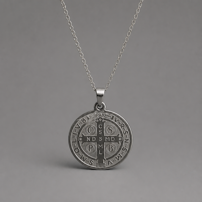 Croatian Medallion Necklace – St. Benedict Catholic Pendant A silver pendant necklace featuring a circular Saint Benedict monogrammed medal on a delicate silver chain, set against a solid gray background.