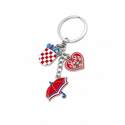 Keyring Traditional Šestinčani A silver metal keychain featuring three Croatian-themed charms: a red and white checkered coat of arms badge, a red heart charm with white script and a central blue rose, and a red umbrella charm with blue and white trim, all attached to a split key ring on a white background.