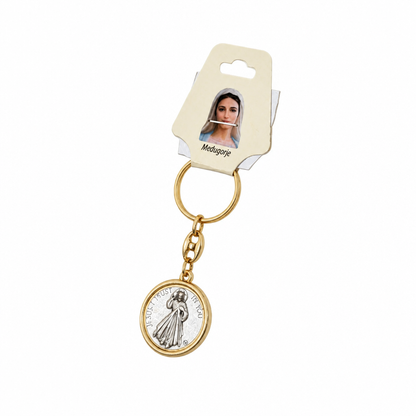 Međugorje Keyring Virgin Mary in Gold A gold-tone and silver-tone Miraculous Medal keychain with its original cream-colored cardboard hanger, shown against a plain white background.