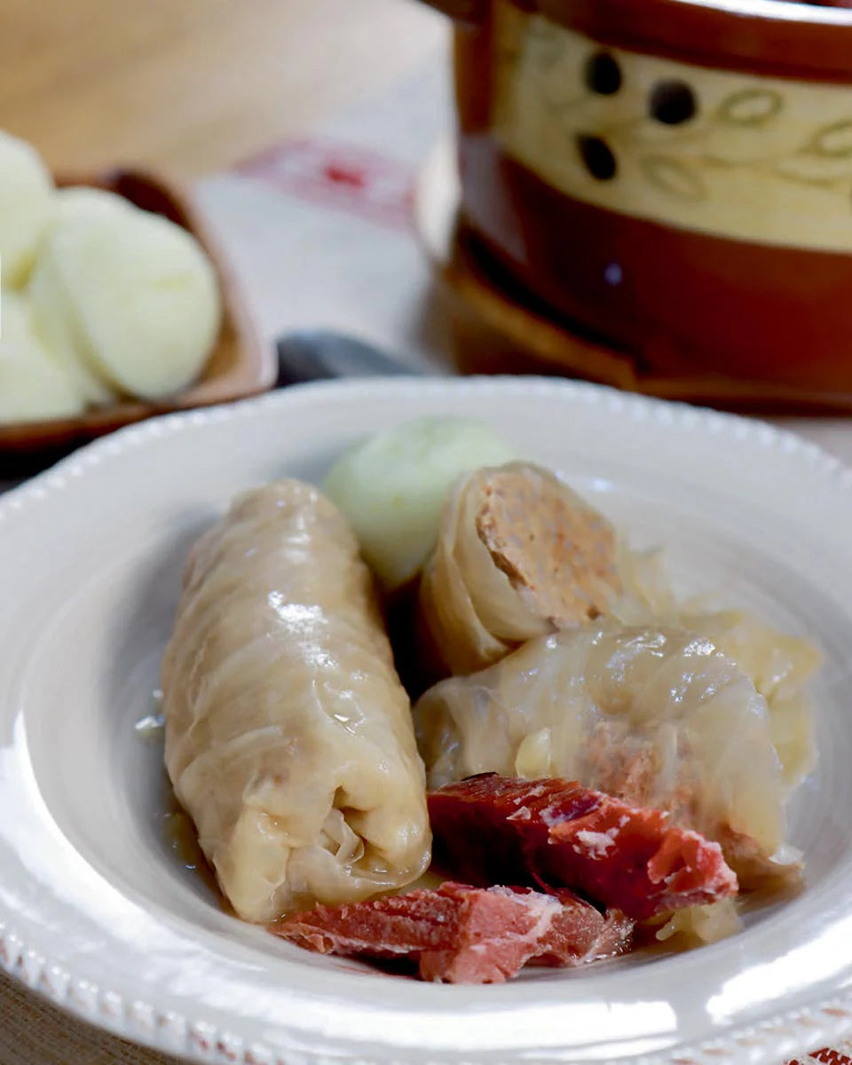 Croatian Classics: Cookbook in English Language Stewed dish with meat and vegetables on a white plate, with a blurred background - Sarma