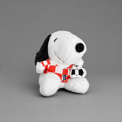 A plush toy of Snoopy wearing a red and white checkered jersey and holding a black and white soccer ball, set against a solid gray background. Singing Croatian Fan Puppy – Hanging Plush Toy