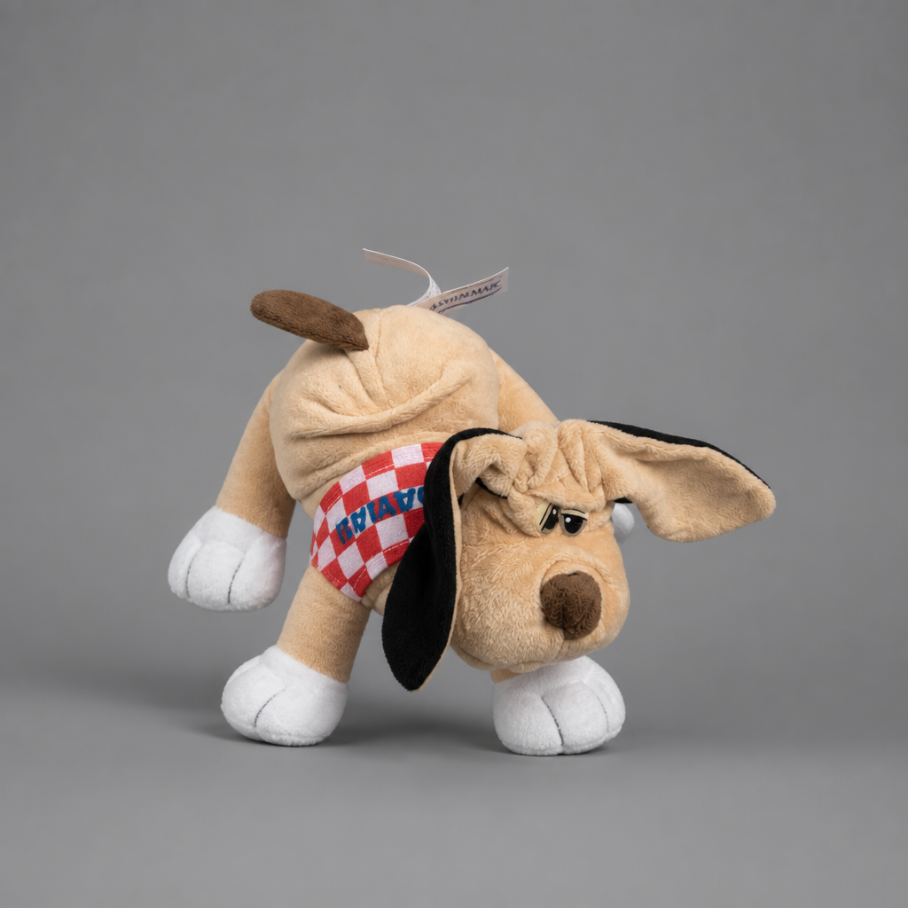 A plush dog toy in tan with white paws and tail, black floppy ears, and a red-and-white checkered bandana that reads 'HVALBA', photographed on a plain gray studio background. Singing Croatian Fan Puppy – Plush Toy