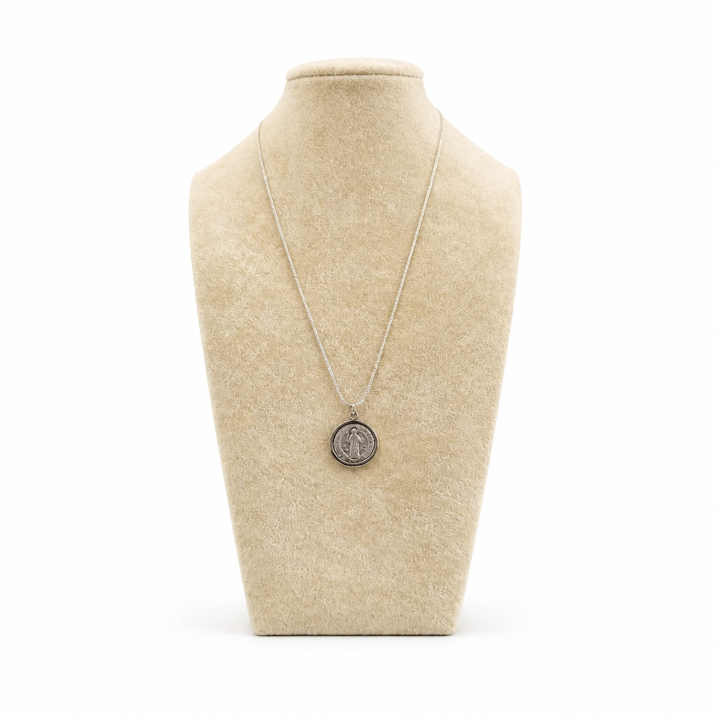 St. Benedict Medal | Pendant + Necklace or Pendant only A silver pendant necklace displayed on a beige fabric jewelry bust against a white background.