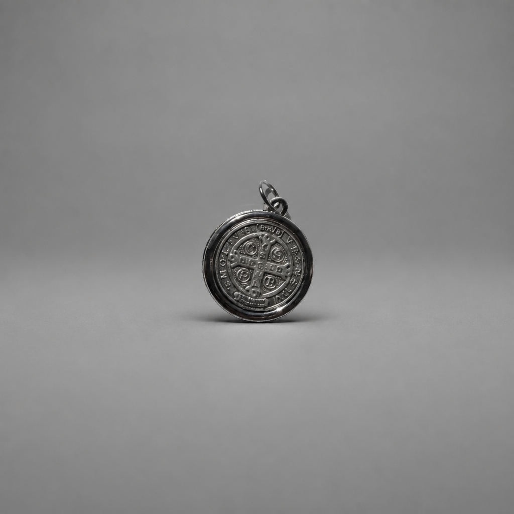 St. Benedict Medal | Pendant + Necklace or Pendant only A round silver pendant with an embossed cross and circular inscription, shown on a neutral gray background.