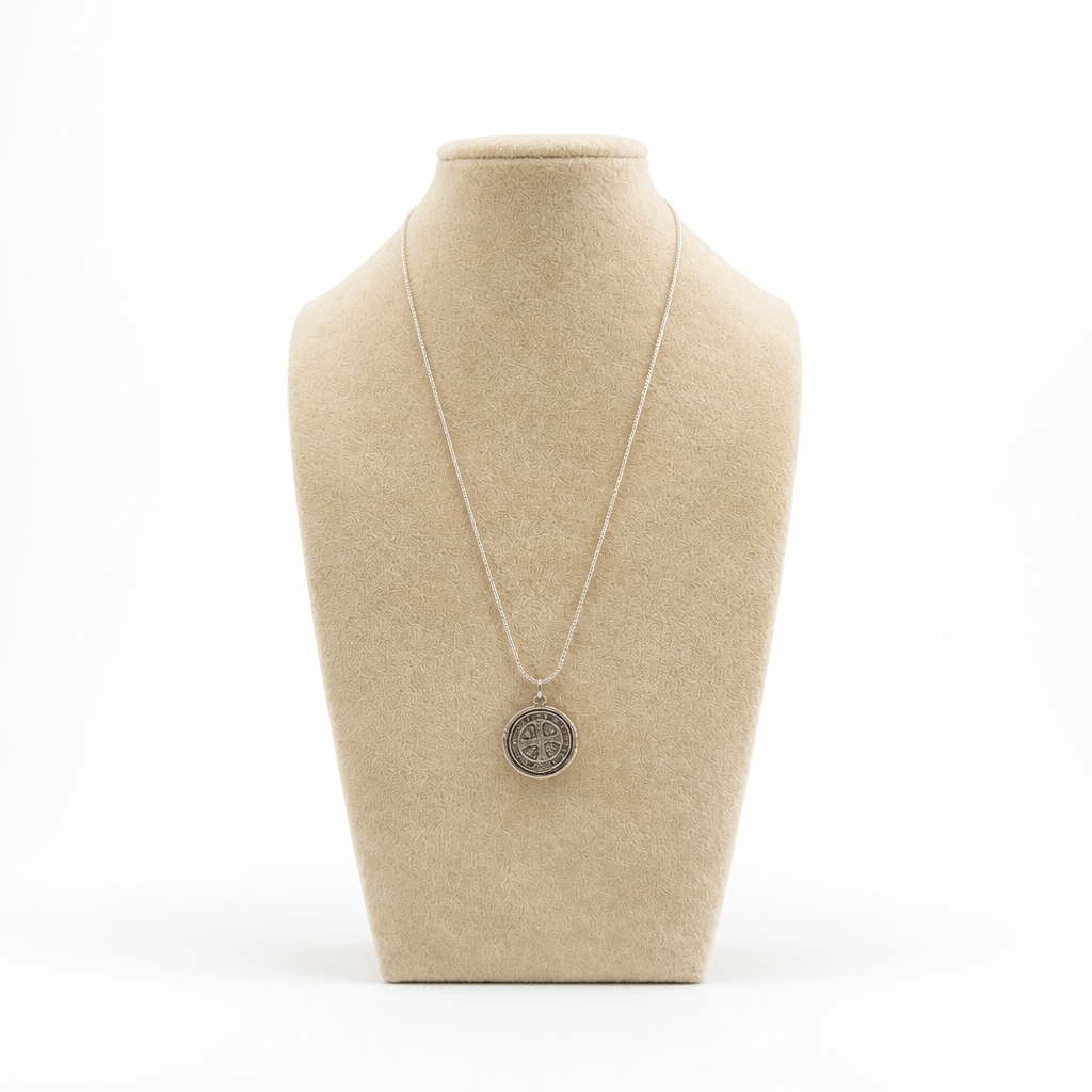 St. Benedict Medal | Pendant + Necklace or Pendant only A silver pendant necklace displayed on a beige fabric jewelry bust against a white background.