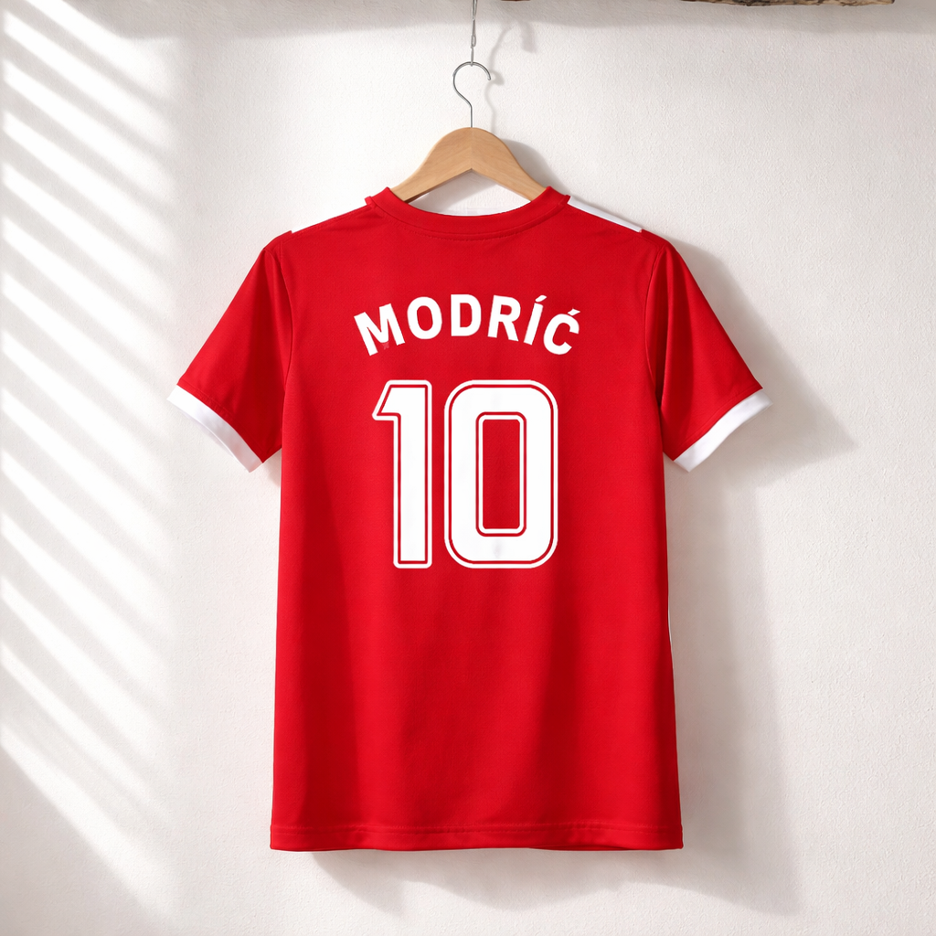 Red sports jersey with 'Modric 10' on a hanger against a white wall.
