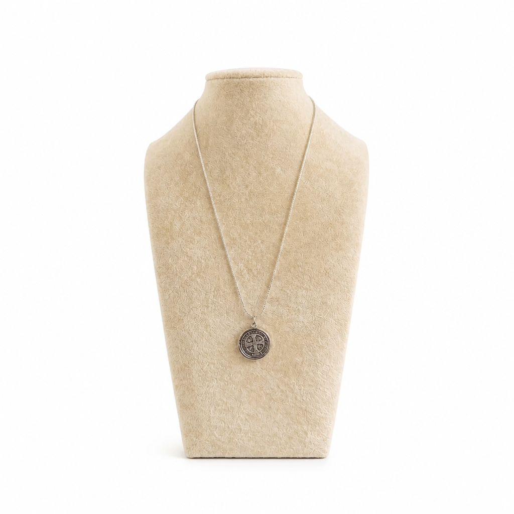 St. Benedict Medal | Pendant + Necklace or Pendant only A silver pendant necklace displayed on a beige fabric jewelry bust against a white background.