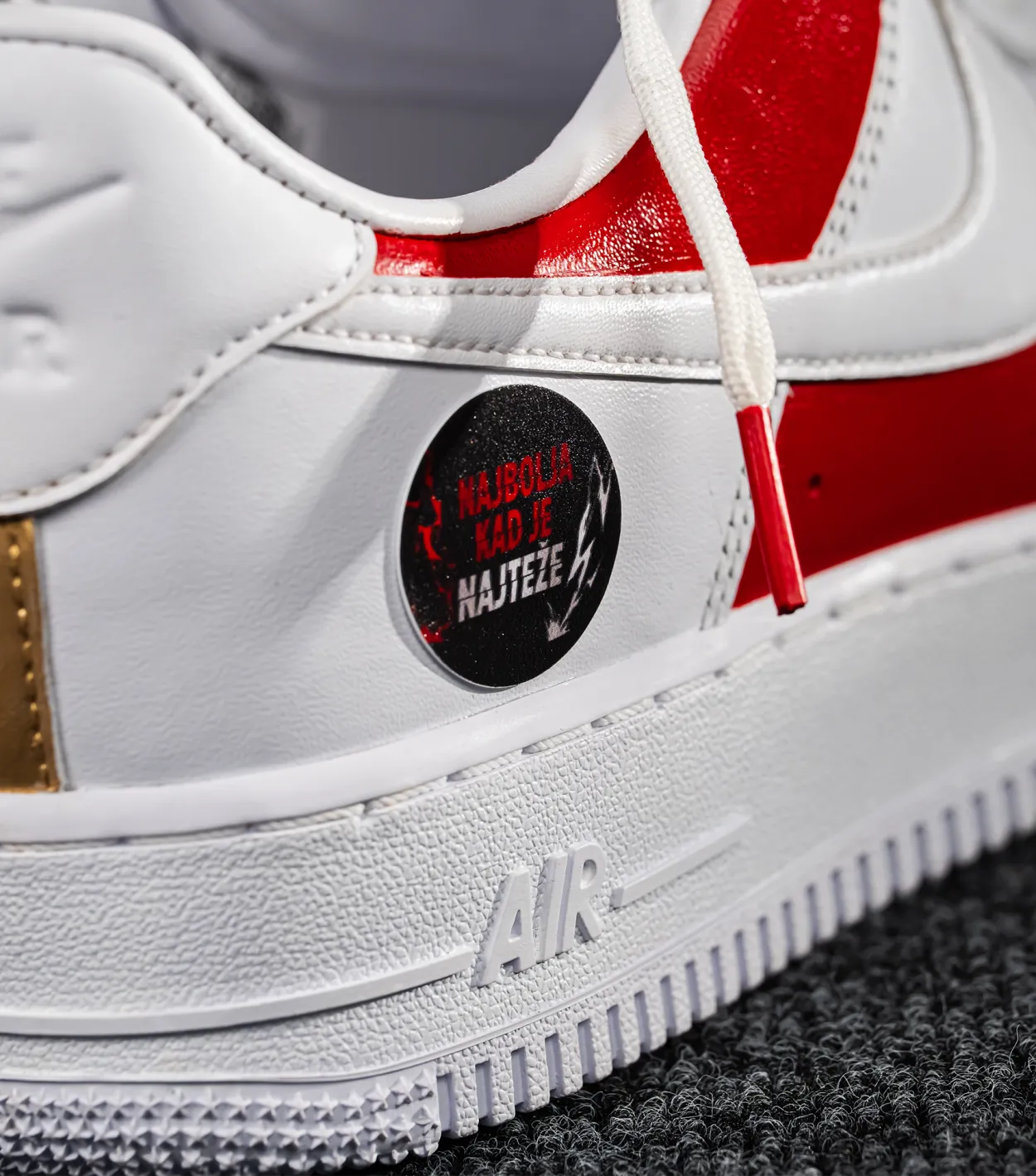 Nike Air Force 1 CROATIA HNS White sneaker with red and gold accents and a black circular label on a gray background shopncro